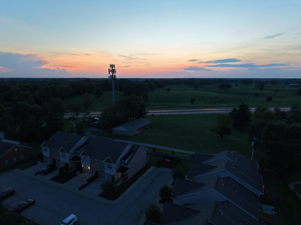 Aerial view of a cell tower at sunset overlooking residential homes and open fields in Lexington, Kentucky.